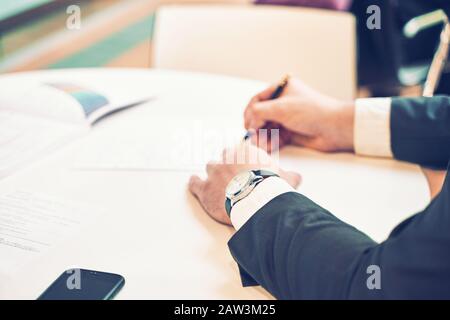 Silhouette of cropped shot of a young man working from home using smart phone and notebook computer, man's hands using smart phone in interior, man at Stock Photo