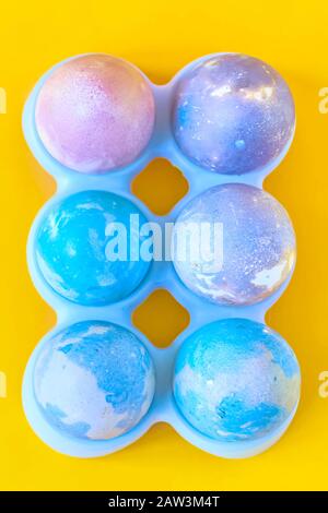 Painted Easter eggs with space intergalactic pattern in stand on yellow background Stock Photo