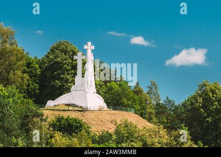 Vilnius, Lithuania. White Monument Three Crosses On Bleak Hill, Overgrown With Lush Green Vegetation In Summer, Blue Sky Stock Photo