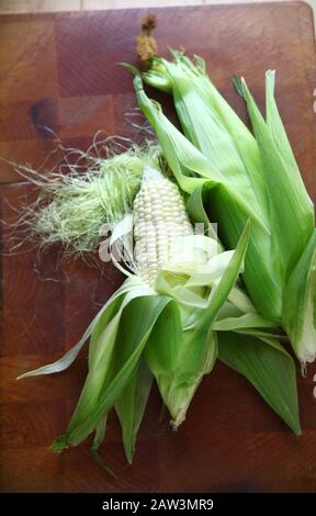 Overhead view of fresh white corn in their husks Stock Photo