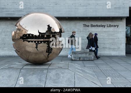 Dublin, Ireland - 29th January 2020:  Students walking by the golden globe sculpture Sphere at Trinity College. Stock Photo