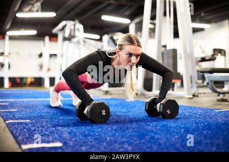 A woman doing push ups on the turf in the gym. Stock Photo