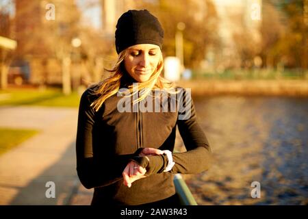 An athletic woman checking her run stats on her smart watch.