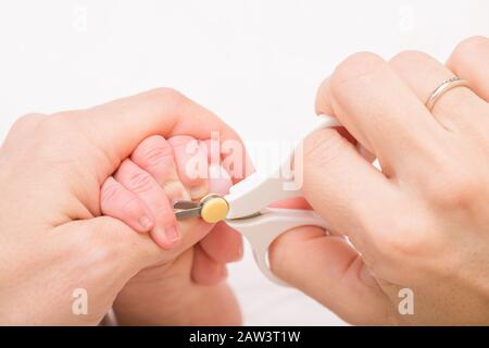 Mother uses special baby nail scissors to trim fingernails of newborn baby to prevent accidental scratching Stock Photo