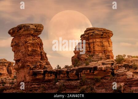 Full moon at it's perigee rising in Maze District at  Canyonlands National Park during sunset Stock Photo