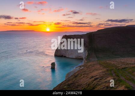 Lulworth, Dorset, UK.  6th February 2020. UK Weather.  A golden sunset at Bats Head near Lulworth in Dorset looking west towards Weymouth and the Isle of Portland viewed from the South West Coast Path on Swyre Head.  Picture Credit: Graham Hunt/Alamy Live News
