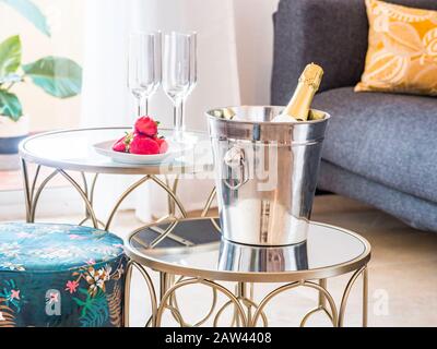 Table with fruit and champagne  in a ice cube in a stylish bright living room with sofa and big window to a terrace with mountain view.Luxury, romanti Stock Photo