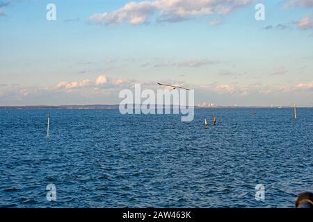 Harbor view at Keyport, New Jersey, with blue skies, a few white cumulus clouds, and a faint Manhattan skyline in the background -07