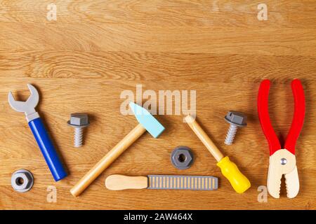 Wooden kids toys screwdriver, plier, bolts, nuts and other construction tools frame on wood background. Top view, flat lay Stock Photo