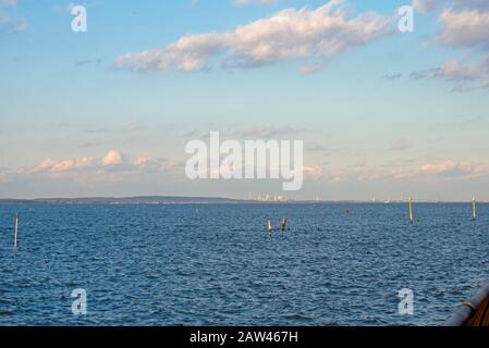 Harbor view at Keyport, New Jersey, with blue skies, a few white cumulus clouds, and a faint Manhattan skyline in the background -08
