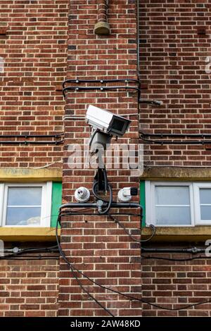 a CCTV camera on the side of a brick building Stock Photo