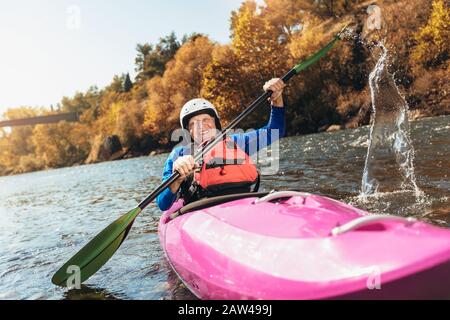 Active senior man paddling kayak. Gray hair man enjoy river kayaking. Stock Photo