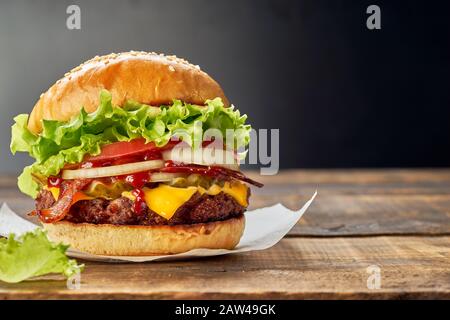 Juicy hamburger on dark wooden table. Copy space Stock Photo
