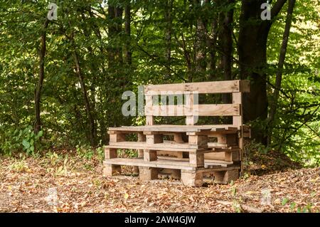 Wooden bench made of old used transport pallets closeup in forest Stock Photo