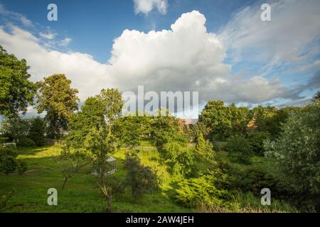 Scenic Summertime View of a Beautiful European rural Landscape Garden with a Green Lawn, Leafy Trees and nice sky with clouds. Czech Republic garden. Stock Photo