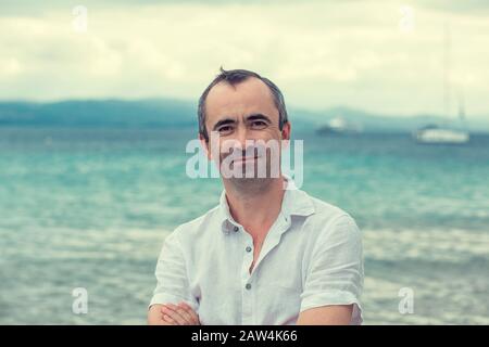 Middle aged man smiling no teeth by the beach in summer Stock Photo