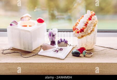 Luxurious natural gemstone Selenite mineral objects at home, candle holder, plate for clearing and loading good energy to gemstones and crystal tower. Stock Photo