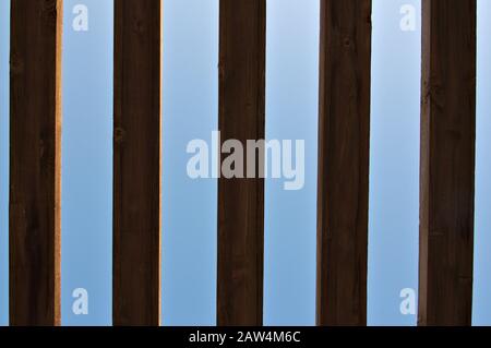 Image taken from below of a roof made with wooden slats that form a dark light pattern between the blue sky and the wood in the shade Stock Photo