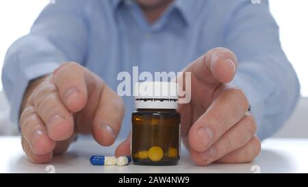 Suffering Businessman at Workplace Taking Few Pills from the Table for a Headache Stock Photo