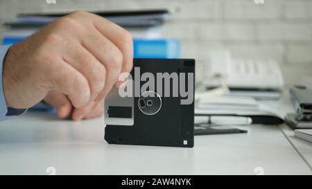 Image with a Businessperson in Office Room Keeping a Floppy Disk in Hand Stock Photo