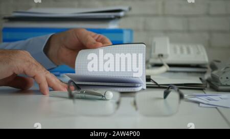 Businessman Working in Office Room Searching Financial Information in Agenda Browsing Page by Page Stock Photo