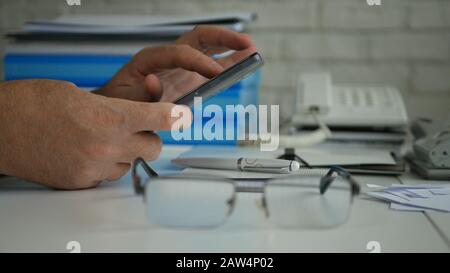Businessman in Office Room Text Sending Business Information Using Cell Phone Wireless Communication Stock Photo