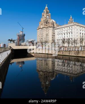 The Liverbird and clock faces on the Royal Liver Building reflect in the canal on the Liverpool waterfront seen in February 2020. Stock Photo