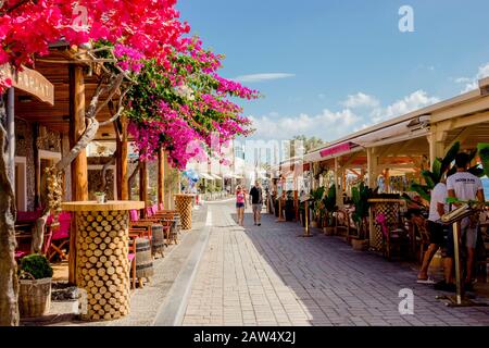 Tourists relaxing on the beach and promenade with hotels overlooking ...