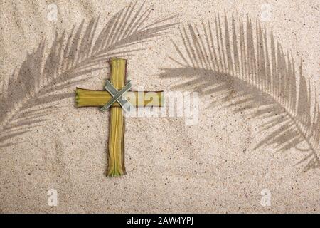 Palm Sunday. Cross and palm shadows on sand background Stock Photo