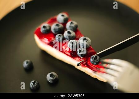 Strawberry cheesecake with blueberries on black plate. Delicious food Stock Photo