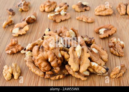 Pile of shelled walnuts on wooden chopping board, macro shot Stock Photo