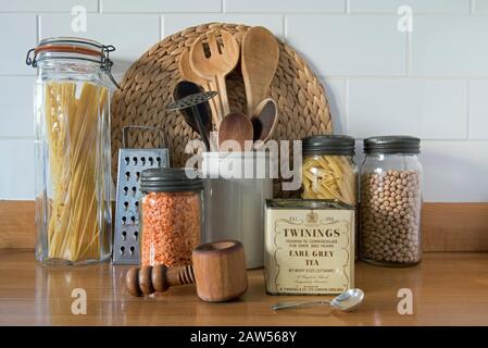 Eco friendly wooden kitchen utensils with vintage glass storage jars and tin of loose Earl Grey tea against white tiles in kitchen, zero waste concept Stock Photo