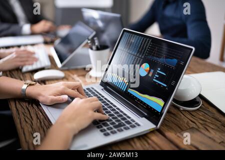 Close-up Of Businesswoman Using Laptop With Graph On Screen In Meeting Stock Photo
