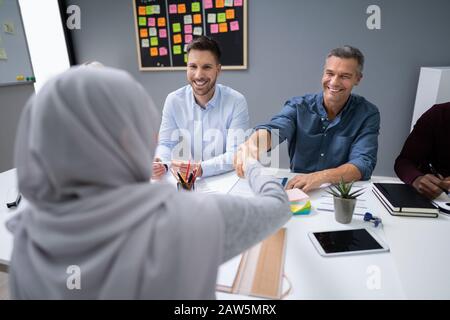 Muslim Woman In Hijab Shaking Hands After Finishing Up A Meeting In Office Stock Photo