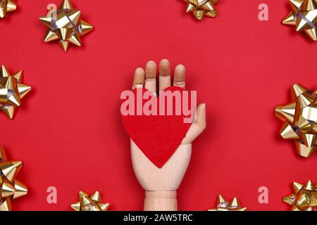 Futuristic image with a robot hand holding red heart on red drop with golden star bows. Robotic, ai, science, connection, technology, humanity concepts Stock Photo