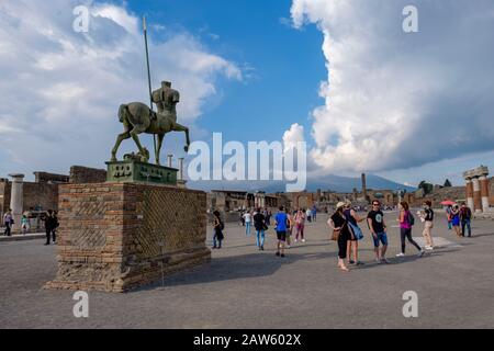 Pompeii ruins, tourists visiting Pompeii Forum - Centauro, bronze statue by Igor Motoraj, Mount Vesuvius on background, ancient city of Pompeii, Italy Stock Photo