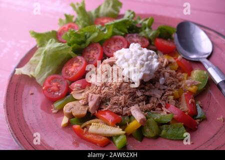 Closeup of tuna and salad on plate on pink background  Stock Photo