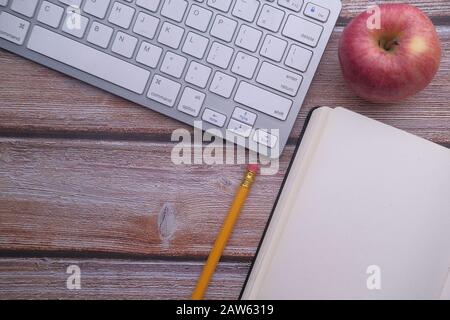 top view of keyboard, pencil, notepad and apple on table  Stock Photo
