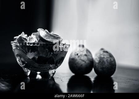 Raw cut aloevera or aloe vera gel in a glass bowl and some fresh ripe lemons or limbu or nimbo on wooden surface along with their reflection on the su Stock Photo