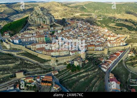 Aerial sunset view of Morella, medieval walled town with semi circular towers and gate houses crowed by a fortress on the rock in Spain Stock Photo