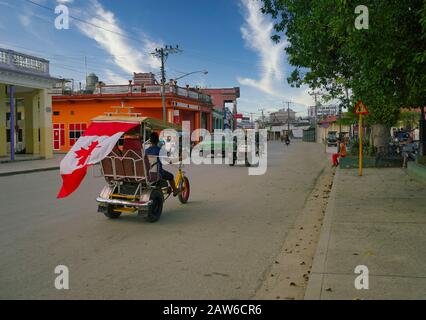 Moron, Ciego de Avila / Cuba - January 20 2020: bicycle taxi with flag of Canada on a busy street. Stock Photo