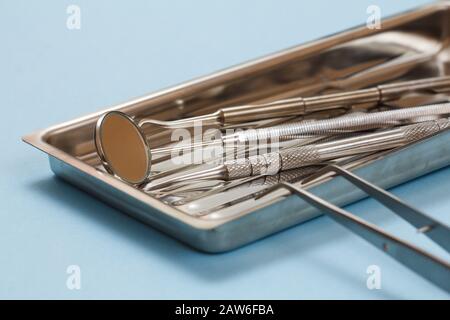 Set of composite filling instruments for dental treatment. Medical tools and stainless steel tray. Focus on a mirror. Shallow depth of field. Stock Photo