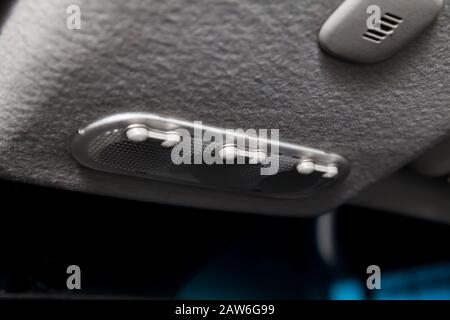 Lighting control inside the car from the top on the instrument panel behind the rear-view mirror in white with buttons. Auto service industry. Stock Photo