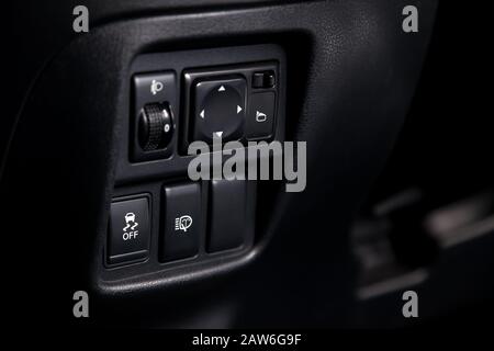 The button for the stability control system, side mirrors adjust and headlight washer on black panel of car near the steering wheel to overcome off-ro Stock Photo