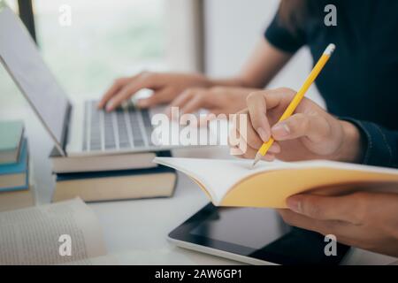 Learning, education and school concept. Young woman and man studying for a test or an exam. Tutor books with friends. Young students campus helps frie Stock Photo