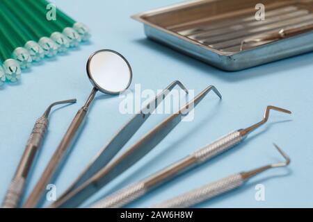 Set of composite filling instruments for dental treatment and saliva ejectors. Medical tools on blue background. Stock Photo
