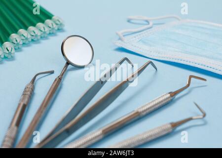 Set of composite filling instruments for dental treatment, mask and saliva ejectors. Medical tools on blue background. Stock Photo