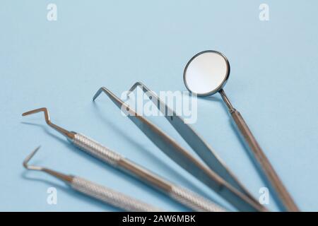 Set of composite filling instruments for dental treatment. Dental mirror, probe, tweezers and scraper on blue background. Medical tools. Shallow depth Stock Photo