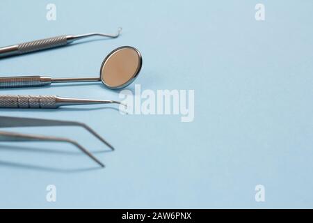 Set of composite filling instruments for dental treatment on blue background with copy space. Focus on a mirror. Shallow depth of field. Stock Photo