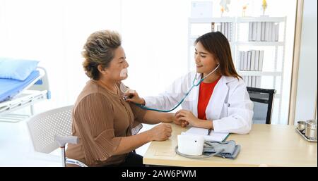 Doctor using stethoscope for examining old women patient in his at Hospitals Stock Photo